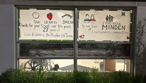 Handwritten signs on Minden ER windows. Text: "Our hearts break as we say farewell to our town of Minden & surrounding communities. Thanks for your trust over the past 27 years! Love & sadness, the Minden ER team."