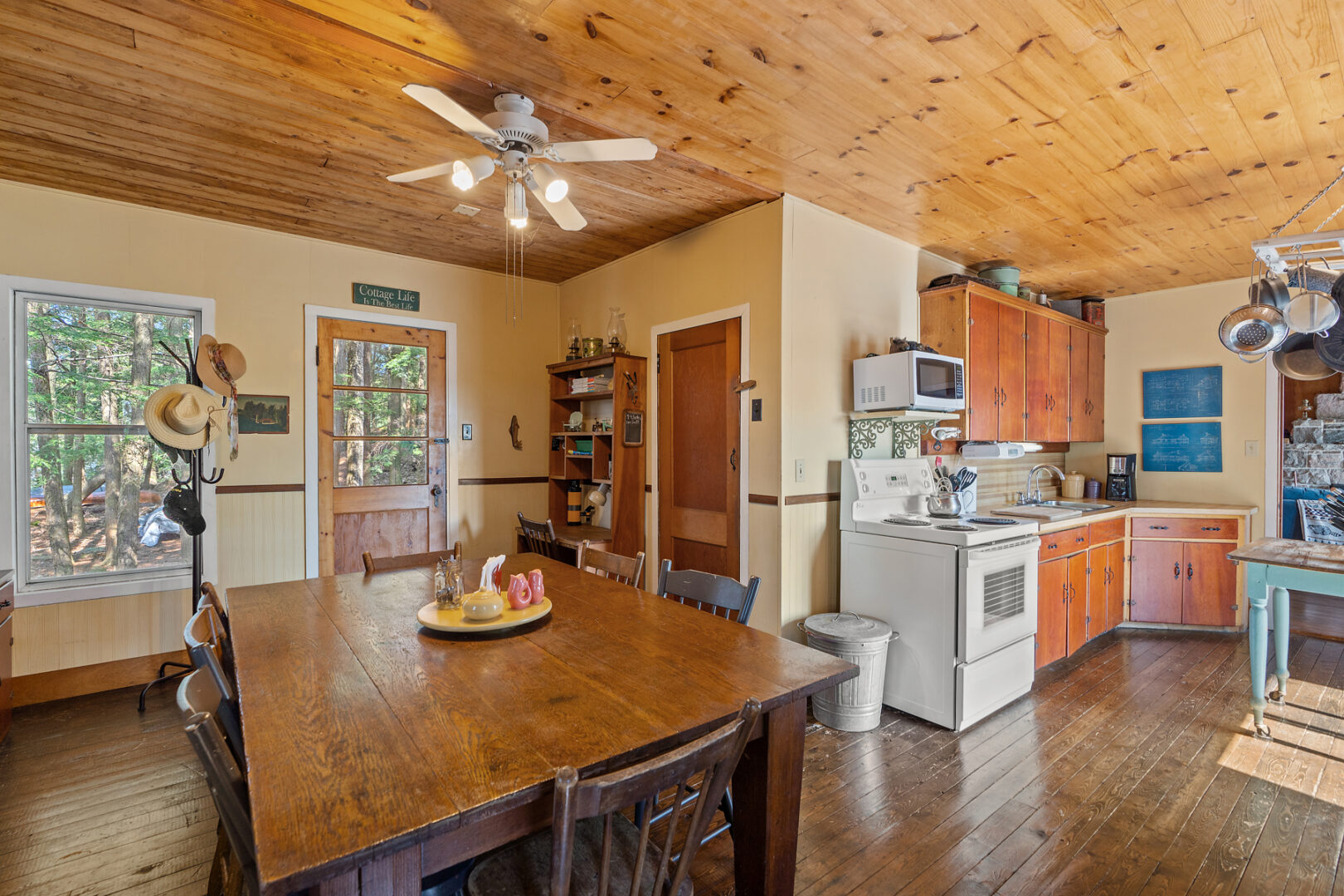 A small cottage kitchen and dining area with a table and chairs, an oven, and wooden cabinets..