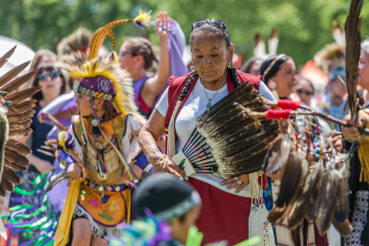 An elder surrounded by youthful and cheerful members of her indigenous community at the 2017 Ottawa Summer Solstice Indigenous Festival at Vincent Massey Park.