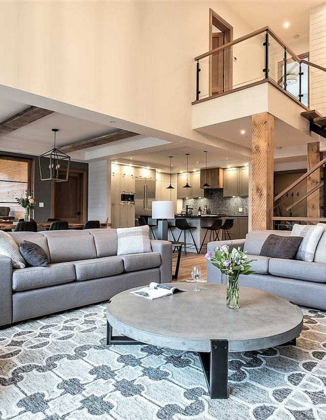 living room with large circular table and patterned rug with vaulted ceilings
