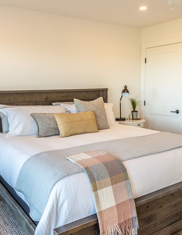 large bed with white bedding and pink plaid blanket
