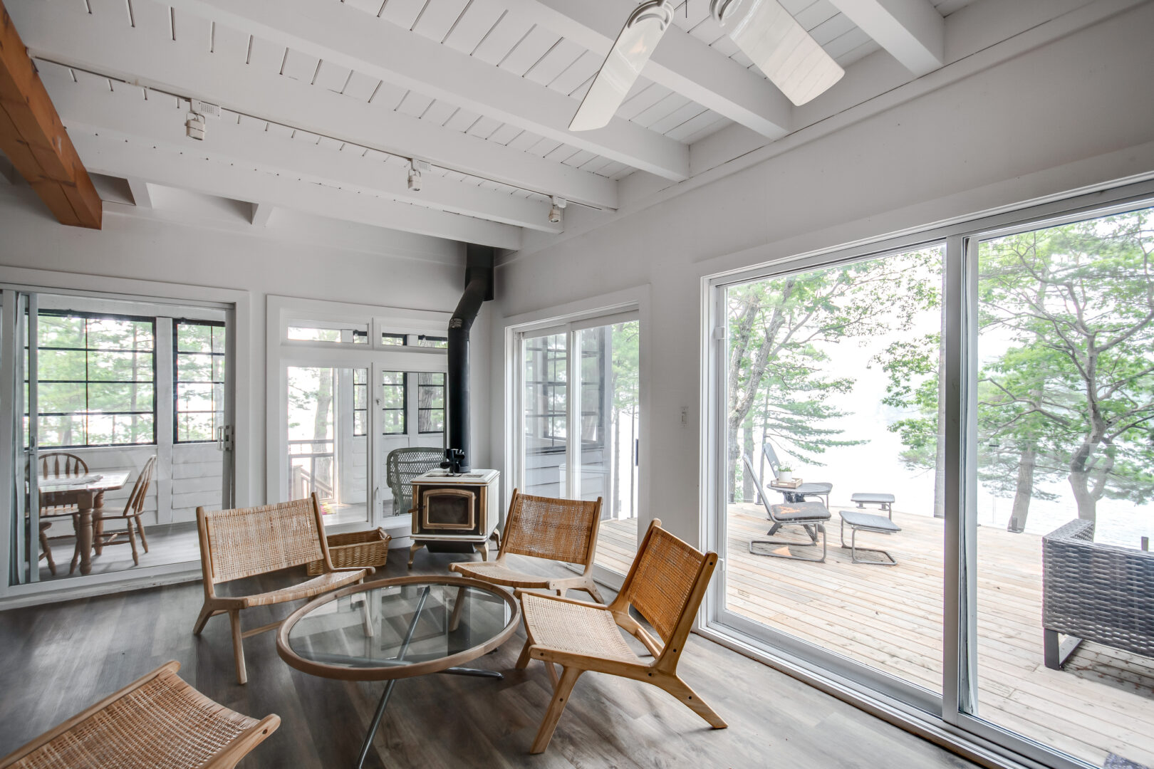 A small area with a table and chairs, a woodstove, and lots of windows, leading into a small sunroom.