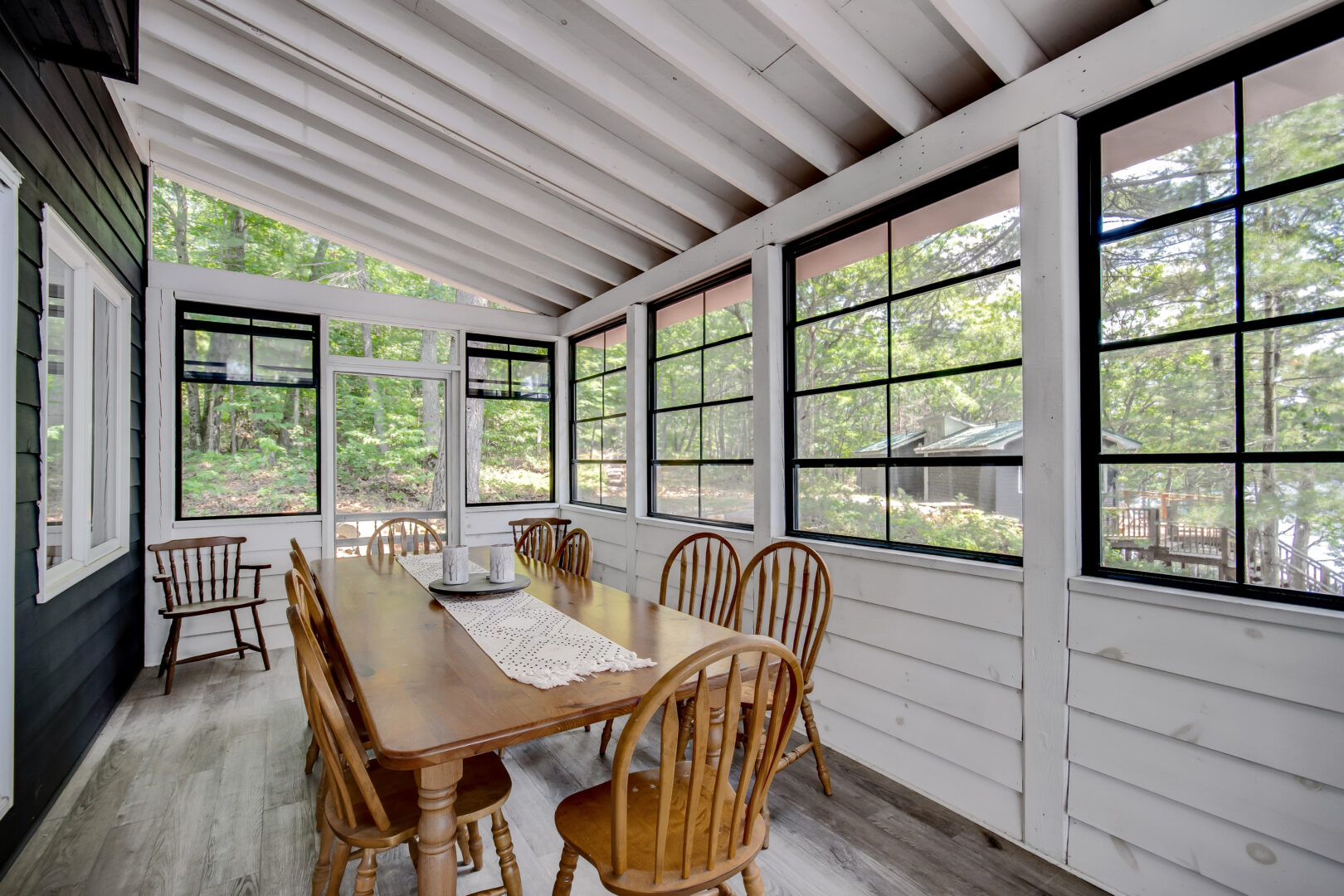 A sunny Muskoka room with a white interior, a table and chairs, and lots of windows.