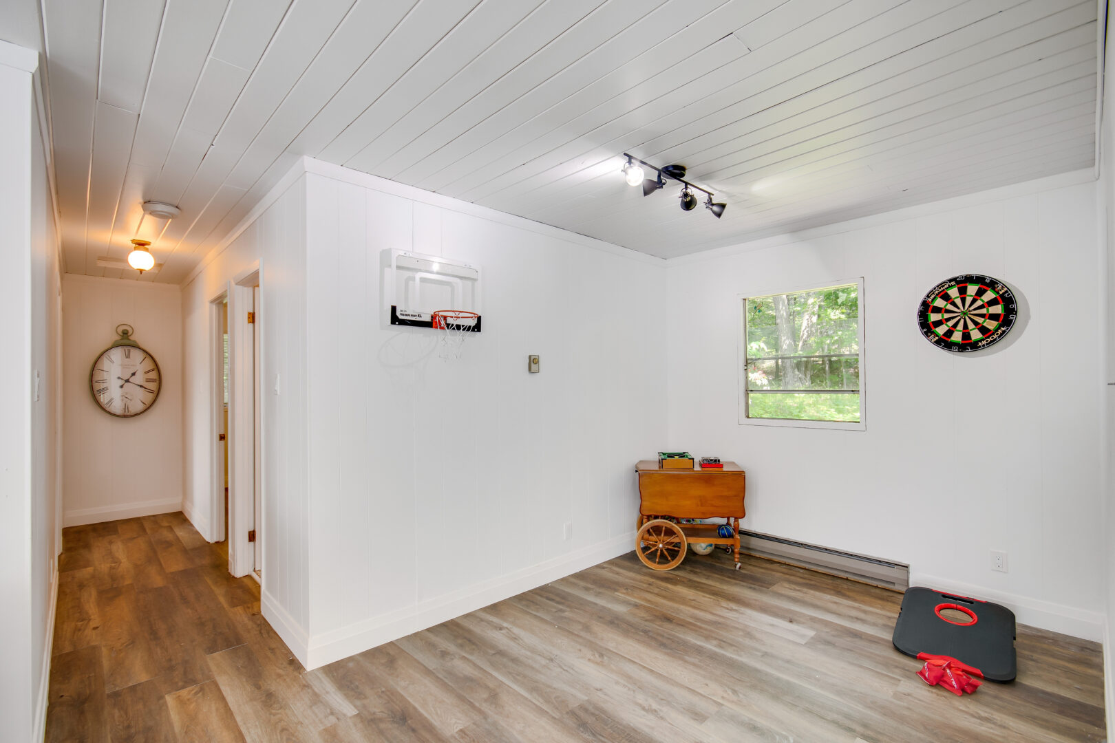 An unfurnished bonus space with white walls, hardwood floors, and a small window.