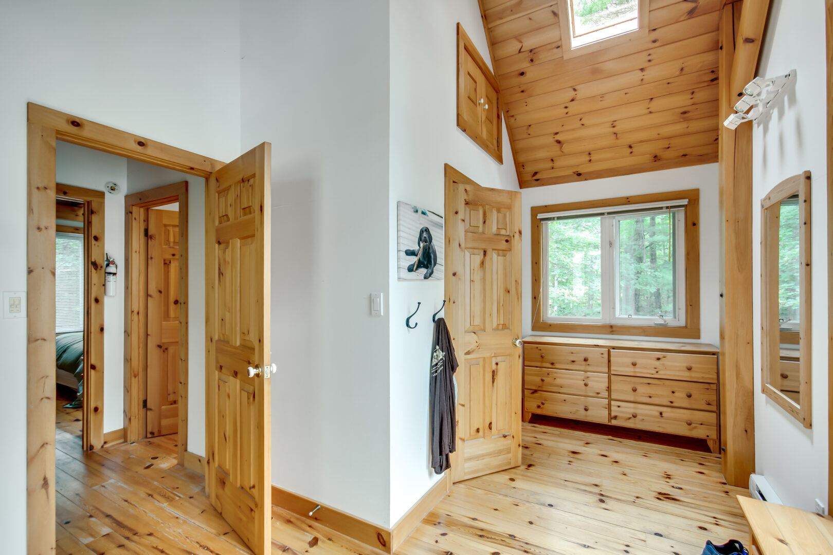 A hallway with white walls, wooden floors, wooden doors, and wood trim.