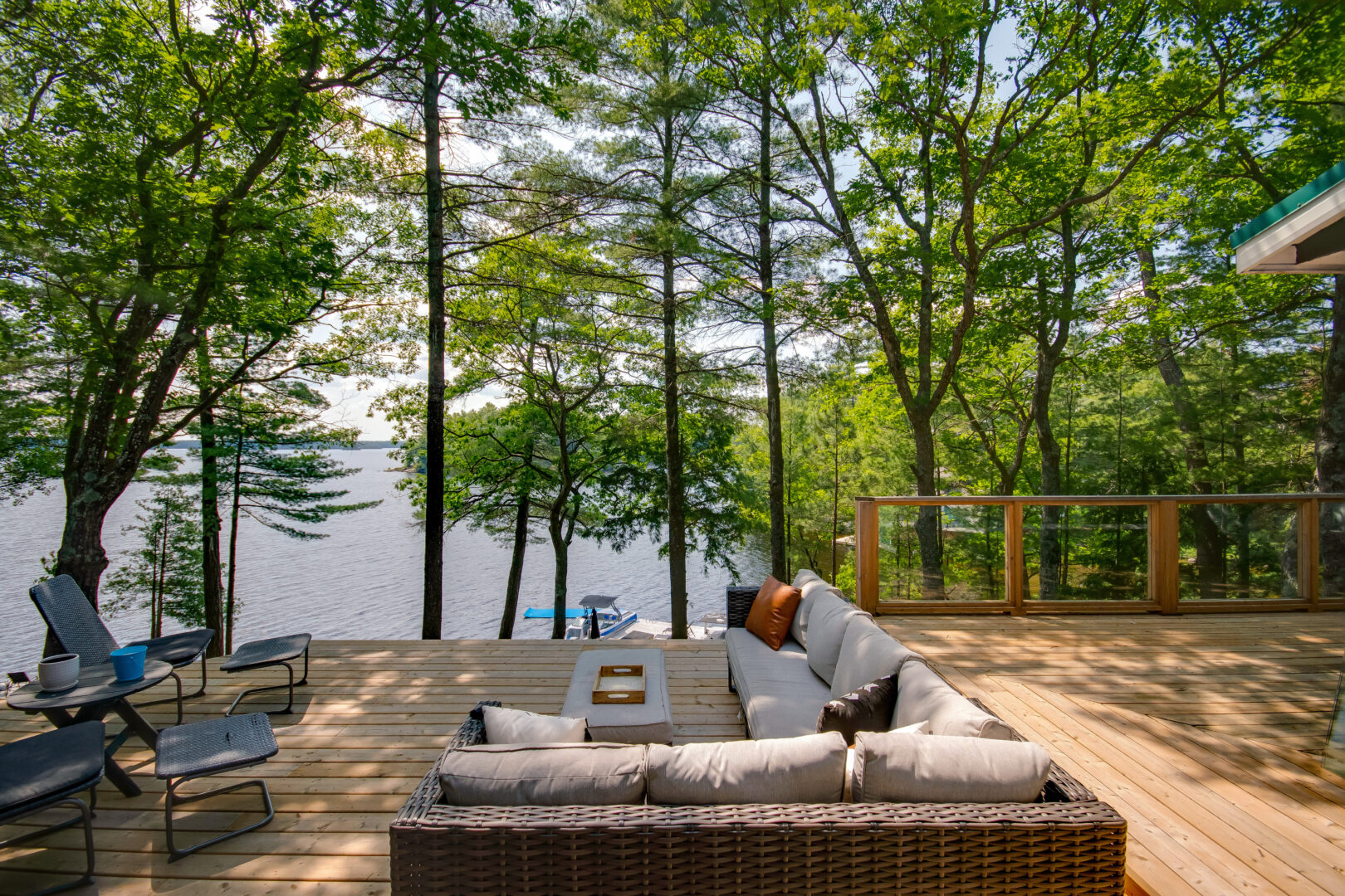 A deck off a cottage with a large couch, looking out over the lake.