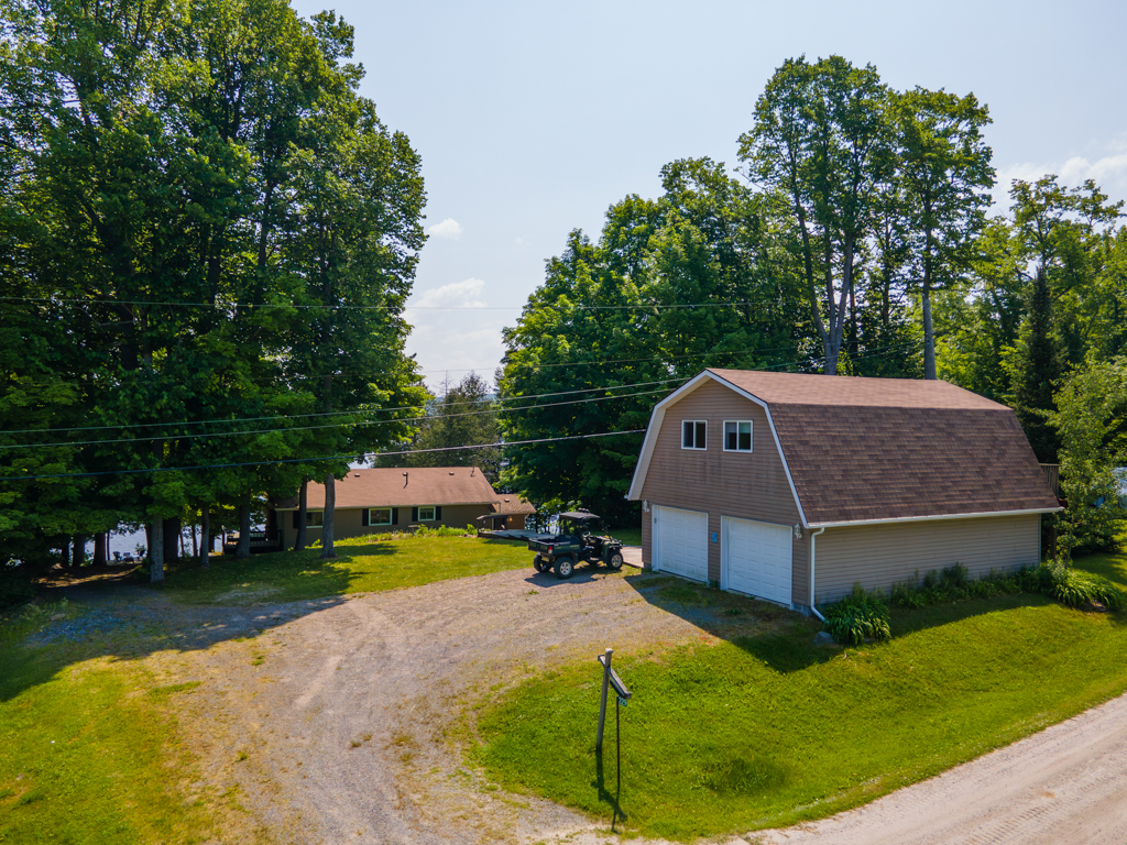 A detached two-car garage sits off a driveway. A house can be seen beyond.