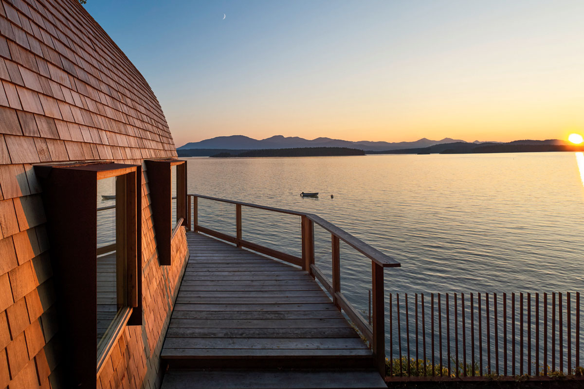 A view of the side of the cabin looking out to the water with the mountains in the distance