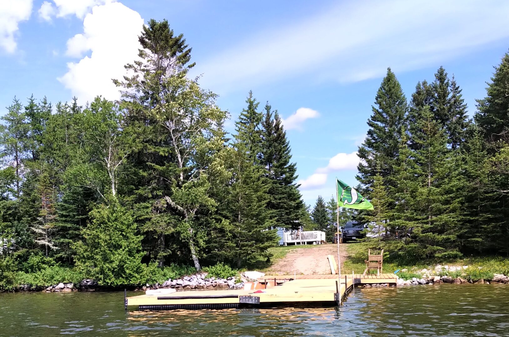 A big dock extends into a lake from a tree-lined shore.