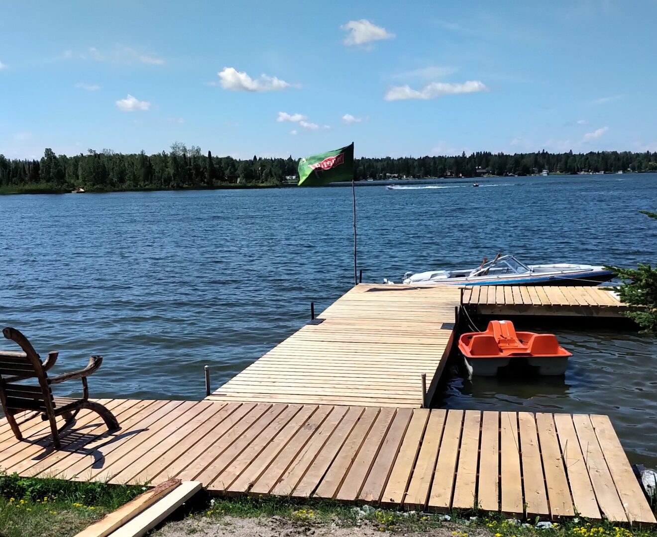 A wooden dock extends into a blue lake.