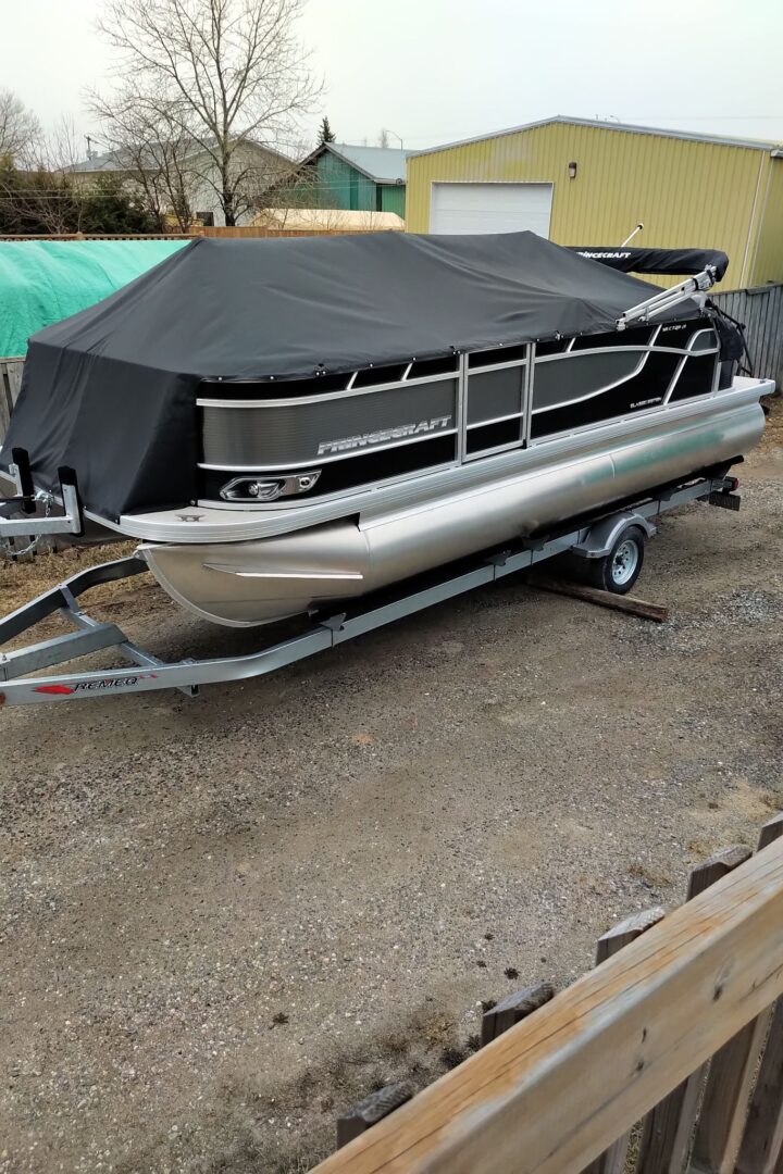 A large pontoon boat sits in a driveway.