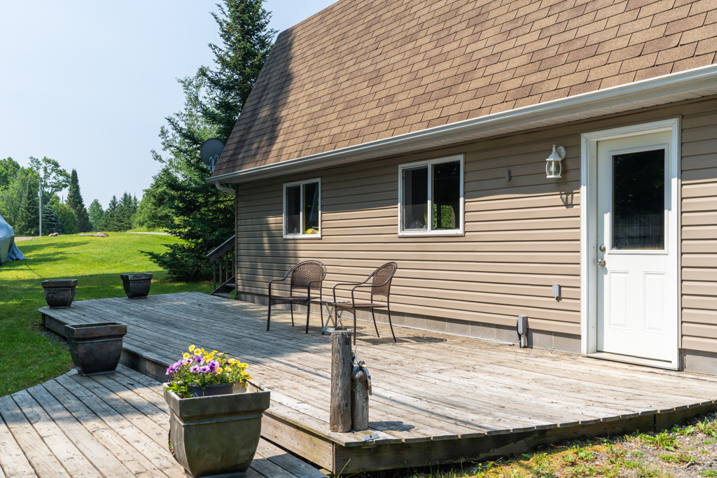 A wooden deck sits in front of a detached garage.