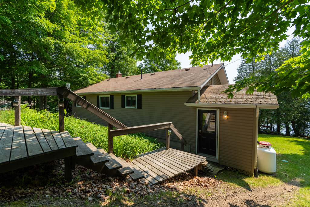 Wooden stairs lead down a sloping hill to a house.