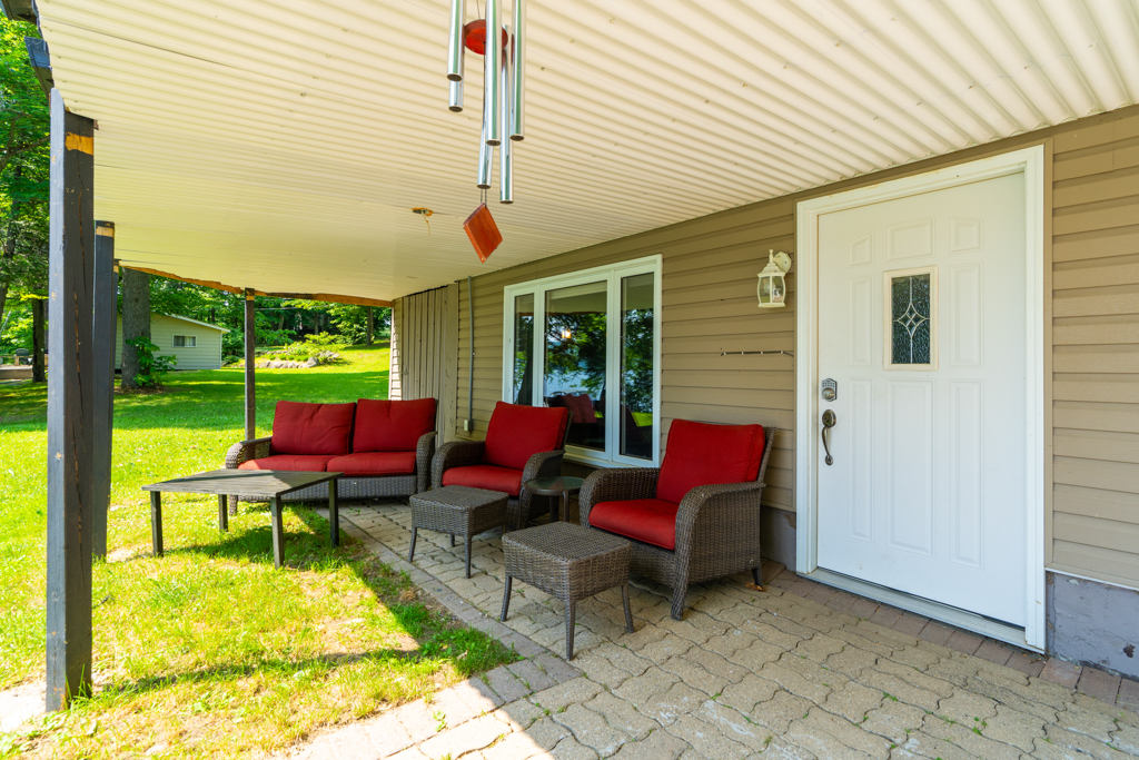A small patio just outside a walkout basement, with red patio furniture.