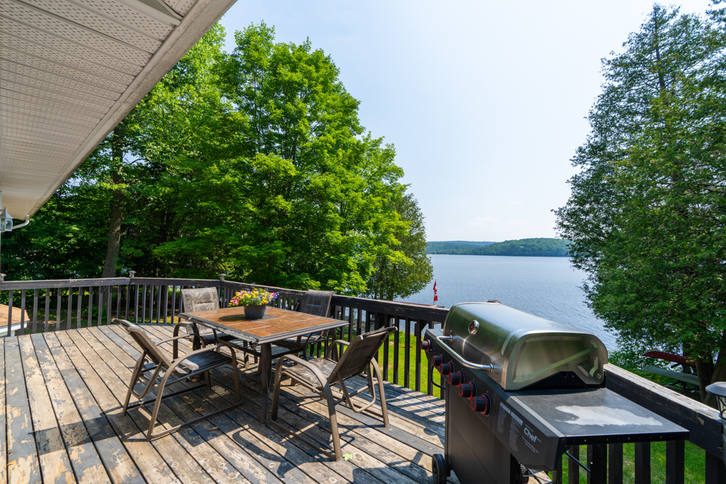 A small second-floor deck with a barbecue and a dining table.