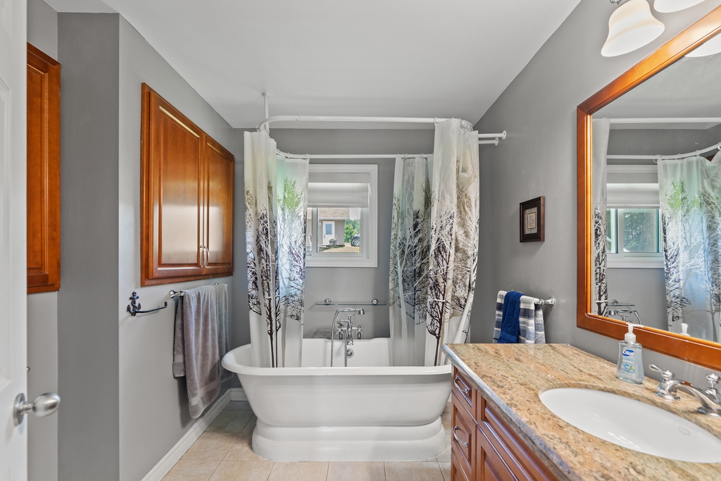 A bright bathroom with a shower-bathtub combo and a sink.