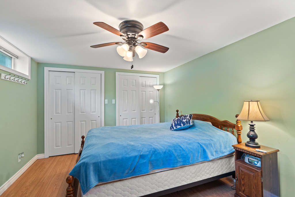 A small bedroom with seafoam green walls, a ceiling fan, hardwood floors, and a small bed.