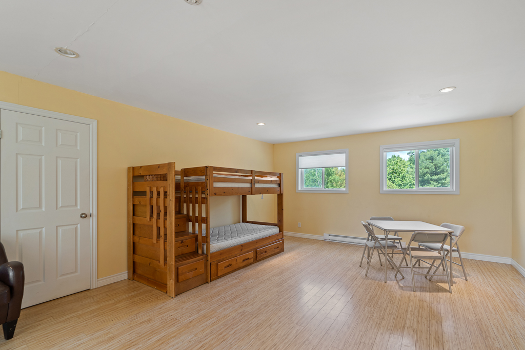 Interior of a bright second-floor loft space in a detached garage, with hardwood floors and a bunkbed.