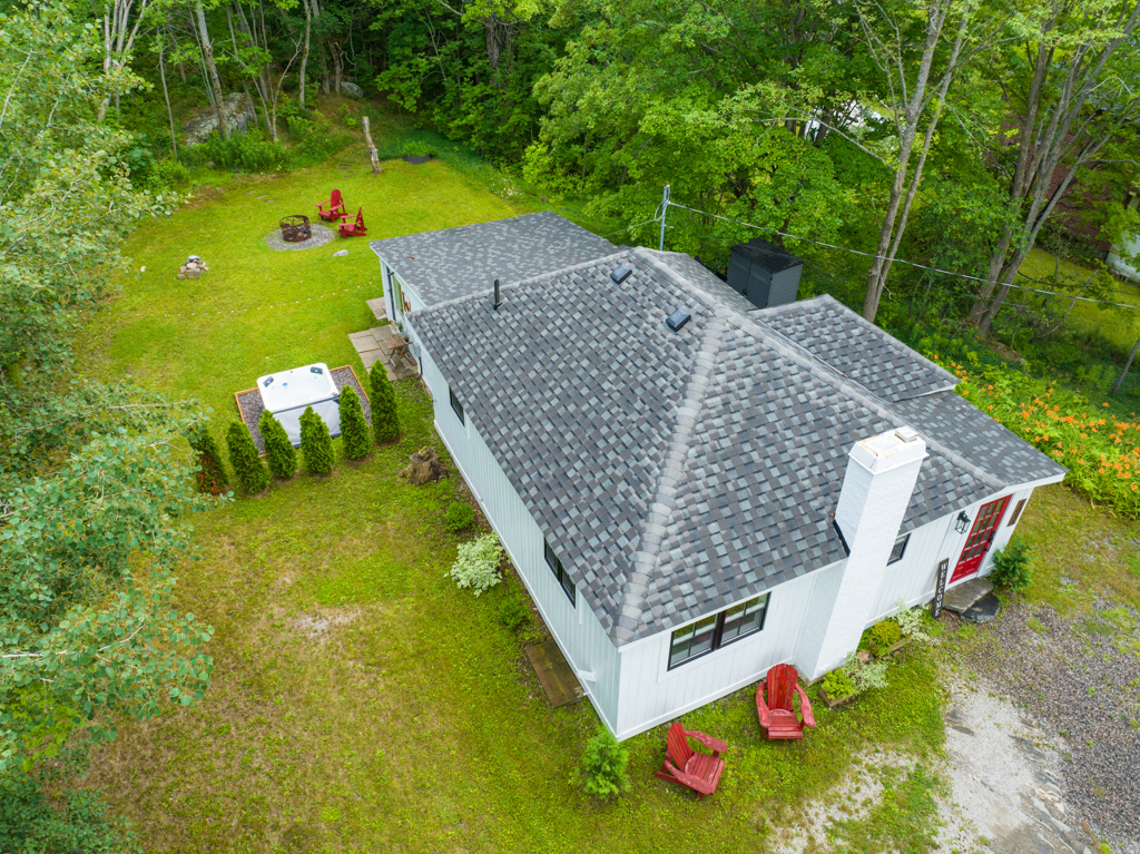 Overhead view of a small house with a gray roof and a big yard.