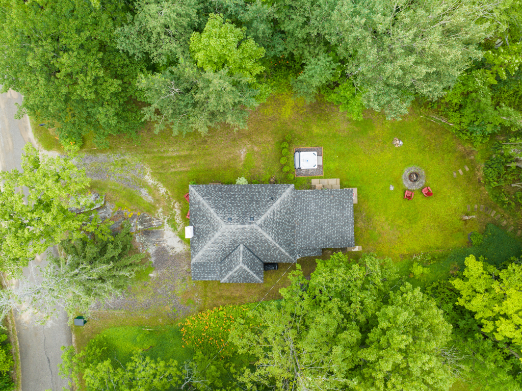 Aerial view of a small house with a gray roof and a big yard.