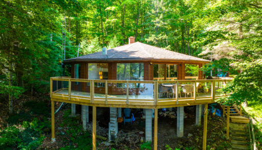 A cottage with a round exterior sits amongst trees.