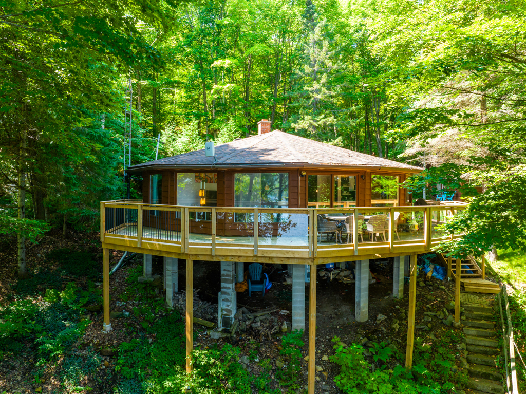 A cottage with a round exterior sits amongst trees.