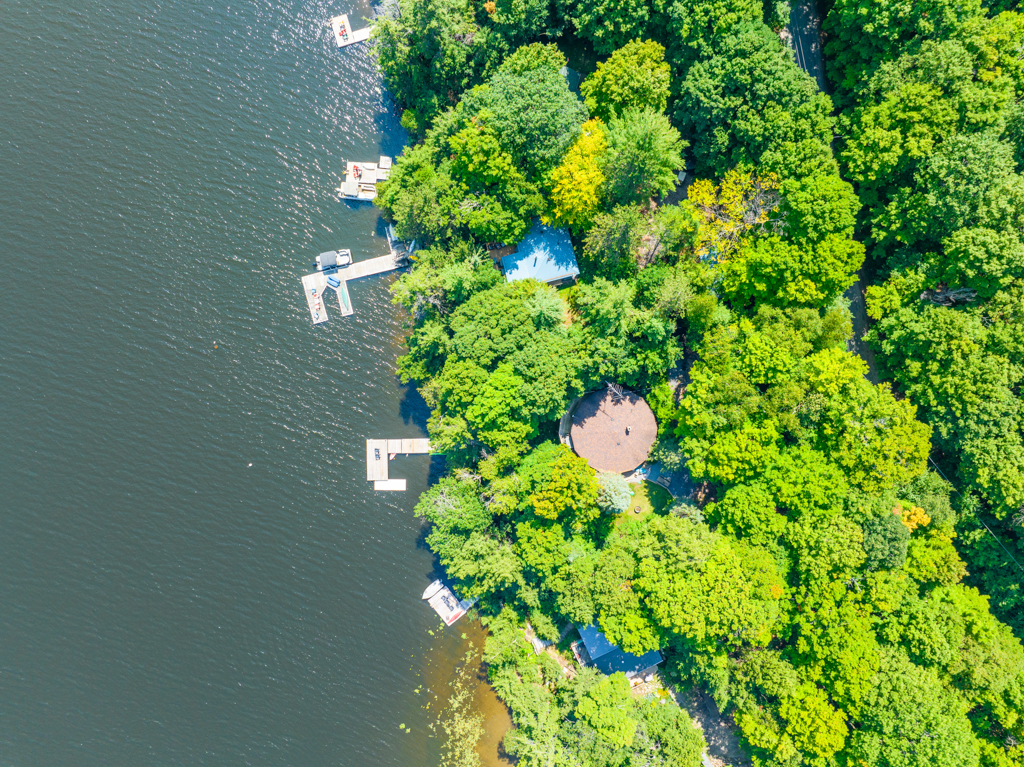 Aerial view of cottages and docks lining the shore of a lake.