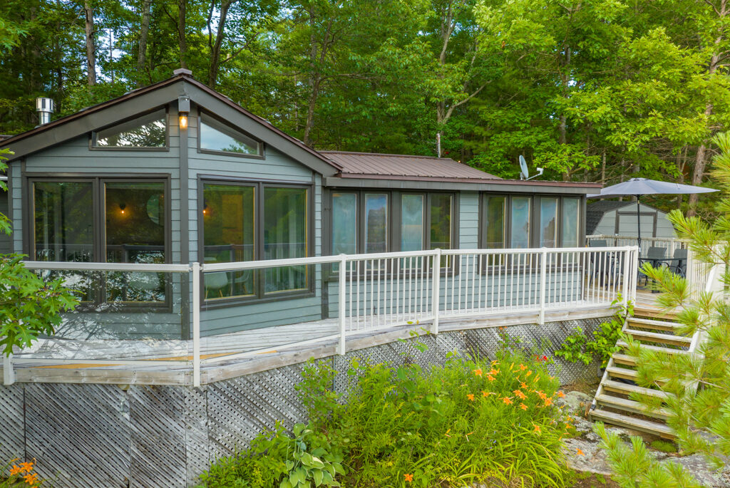 A large cottage with big windows and a long deck.