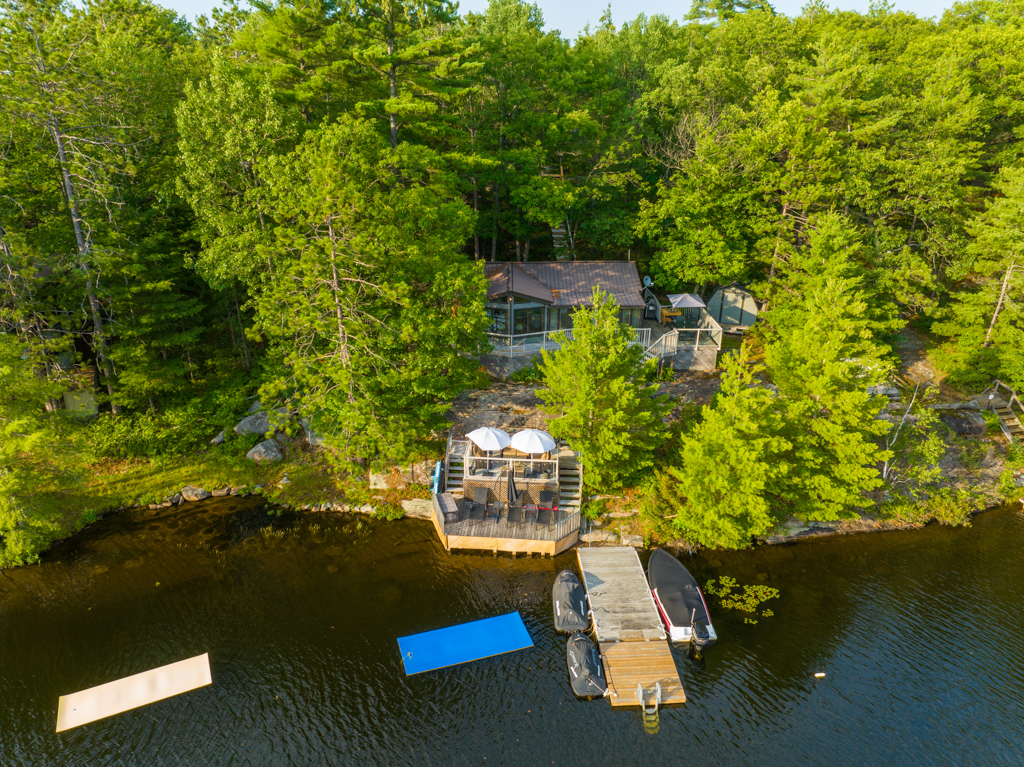 A long dock stretches into a lake, in front of a big cottage property.