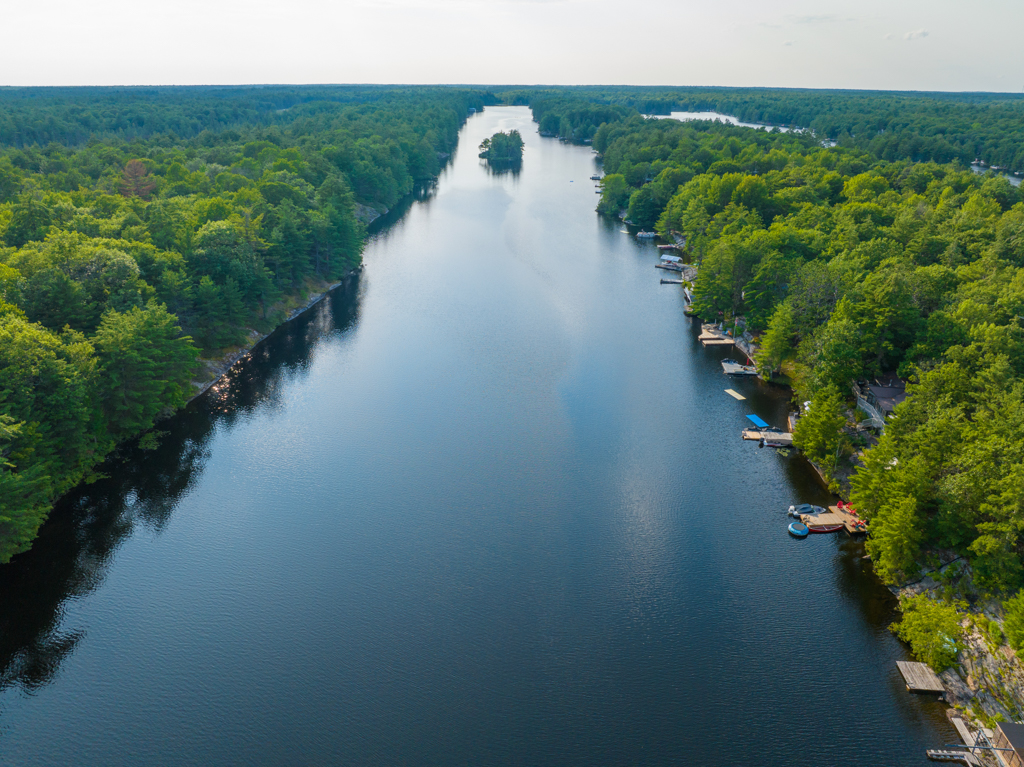Overhead view of a narrow stretch of lake, with green trees on either side.