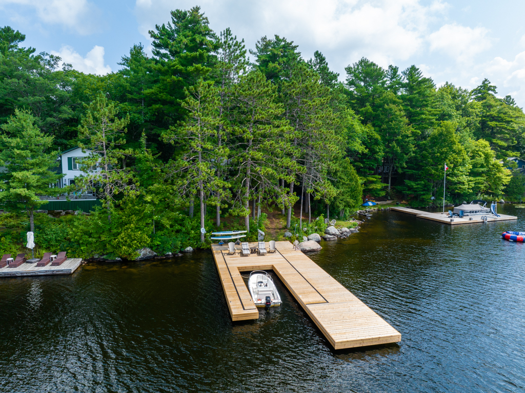 A big, new dock extends into a lake from a tree-lined shore.