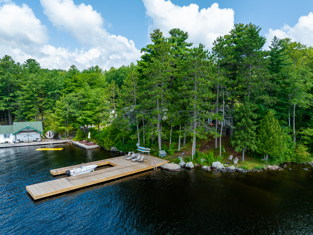 A big, new dock extends into a lake from a tree-lined shore.