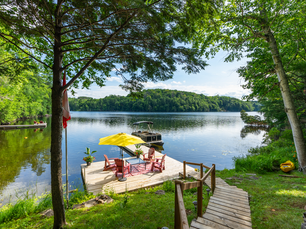 Wooden stairs lead down to a dock on a still lake.