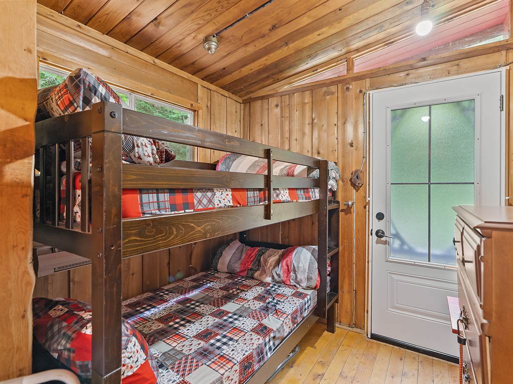 A small bedroom with bunkbeds and a door leading outside.