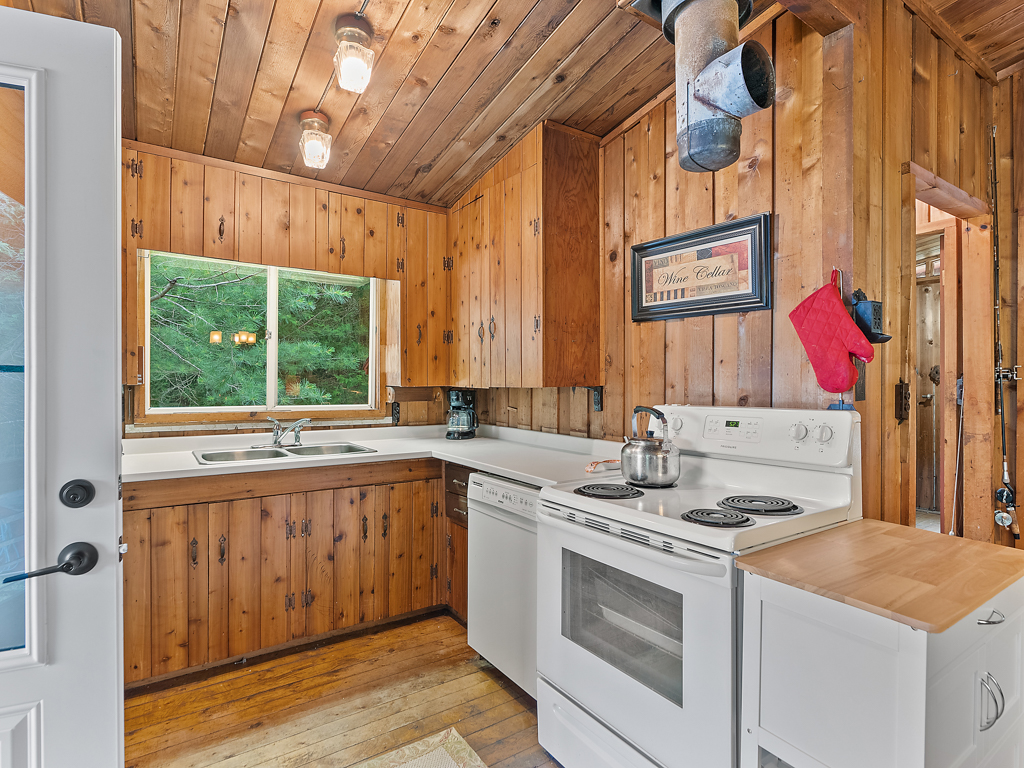 A small kitchen with an oven, a sink, a fridge, and a dishwasher.