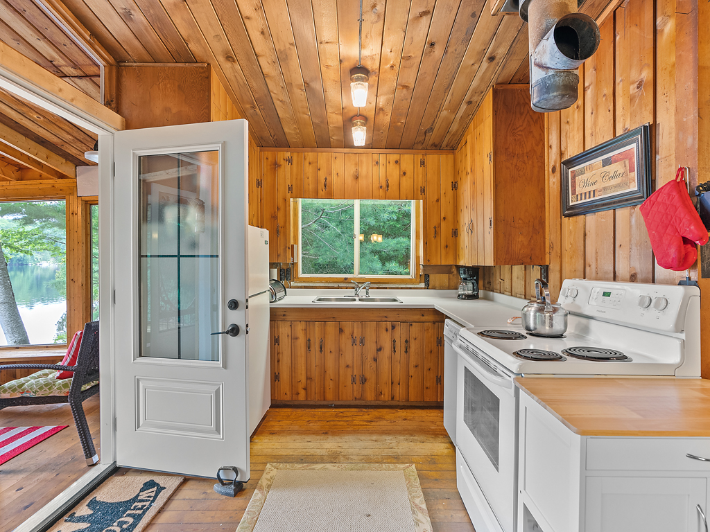 A small cottage kitchen area with an open door leading to a sunroom.