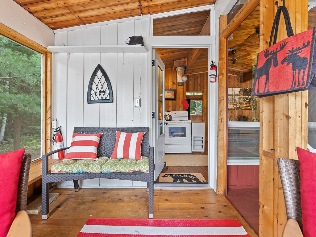 A small, bright sunroom with an open door that leads into a kitchen space.