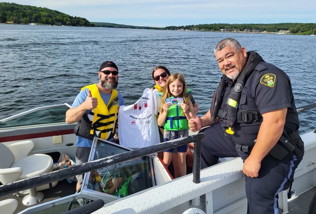 OPP officer posing with family receiving "I got caught wearing my lifejacket" shirt