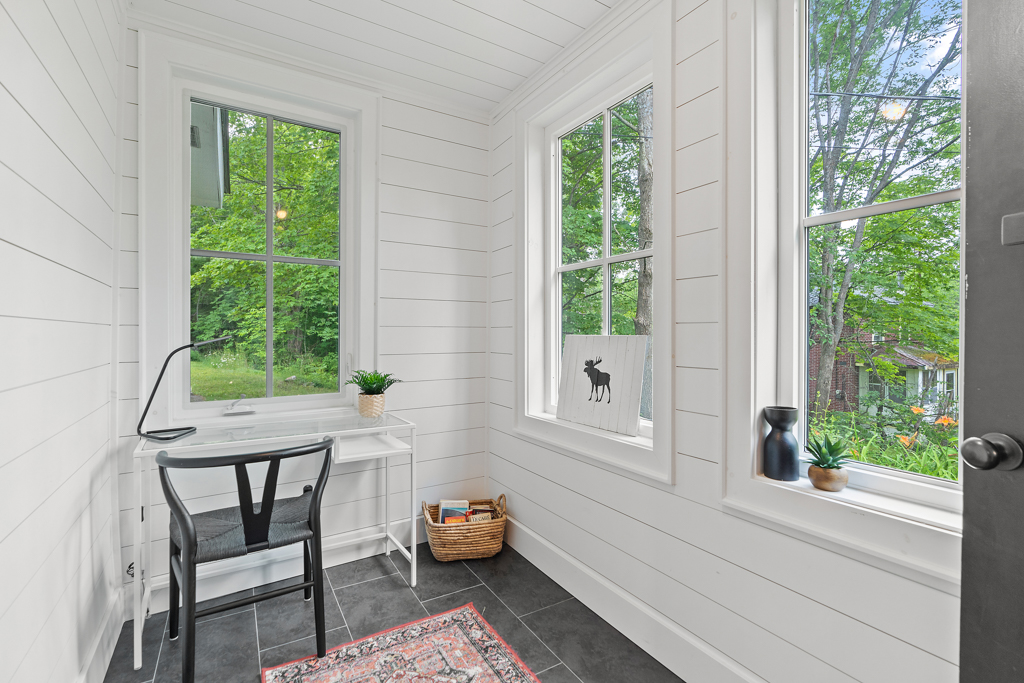 A small space with lots of windows and a small desk.