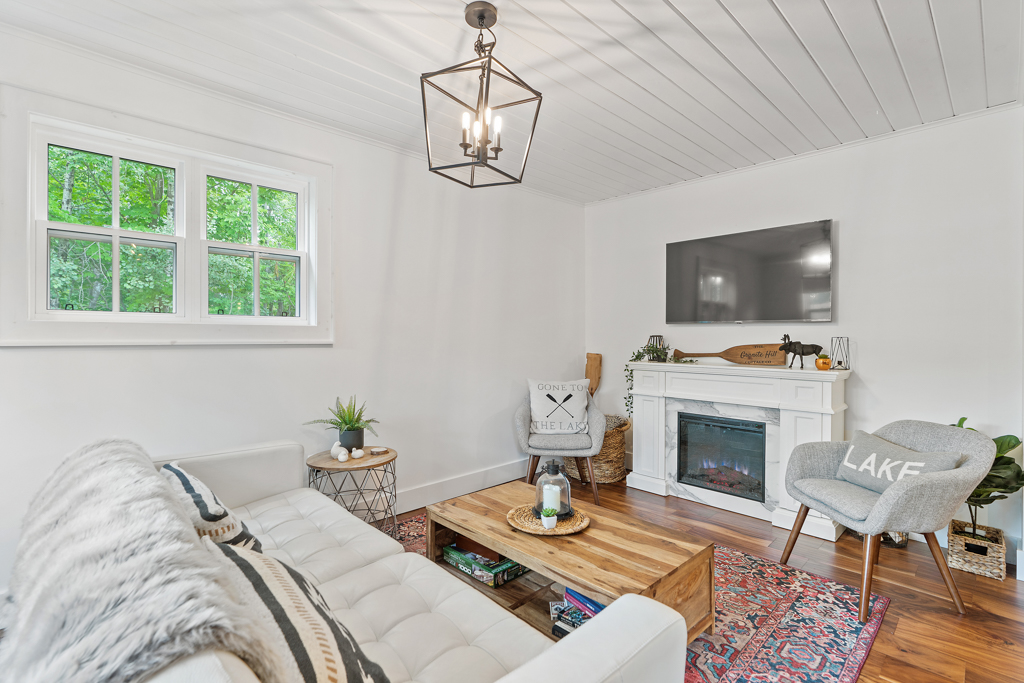A bright living area with hardwood floors, gray couches, a fireplace, and a television.