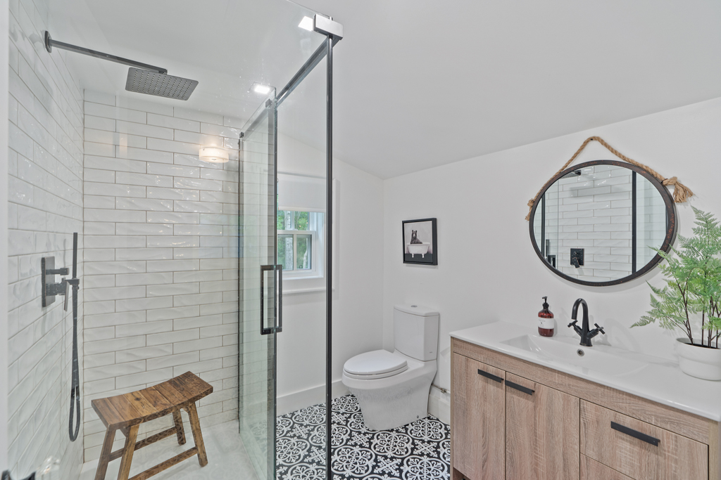 A bright, modern bathroom with tiled floor, a toilet, a sink, and a walk-in shower.