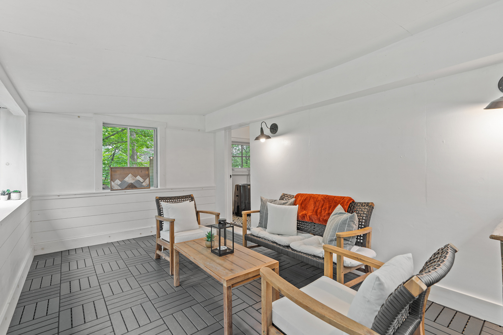 A bright sunroom sitting area with chairs, a couch, and lots of windows.