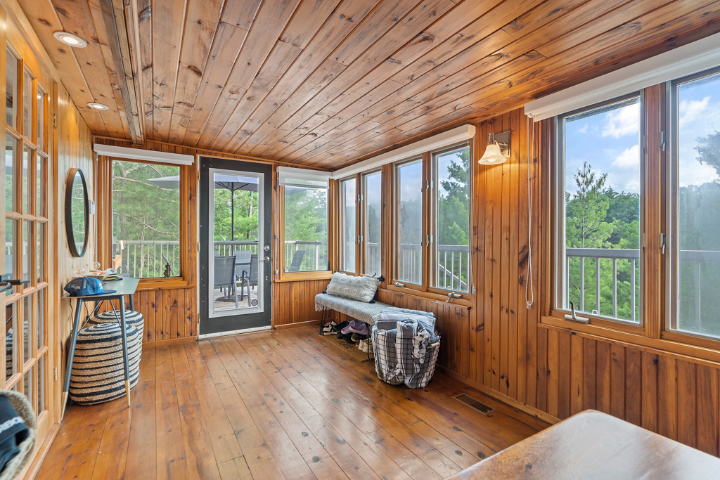 A big, wood-panelled sunroom with lots of windows and a door leading outside.