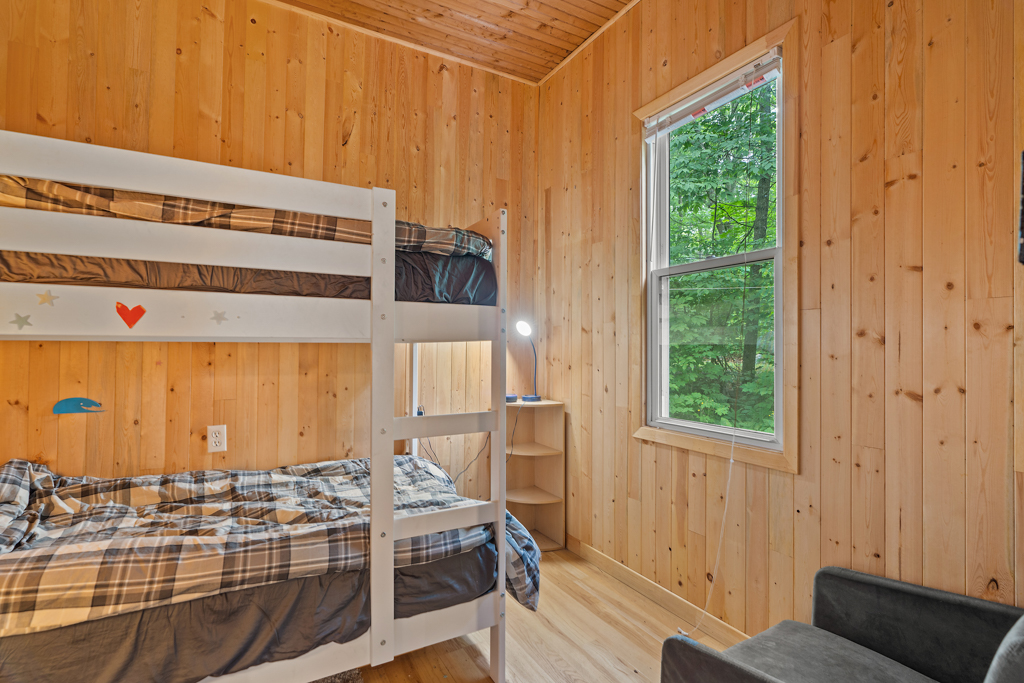 A small bedroom with wood-panelled walls and bunkbeds.