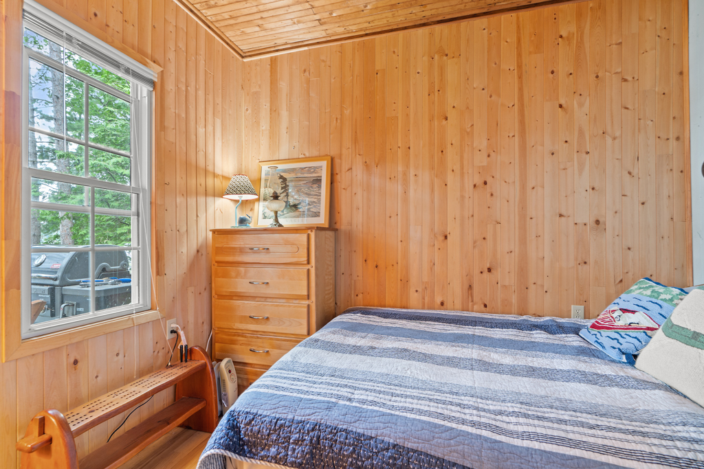 A small bedroom with wood-panelled walls and a bed.