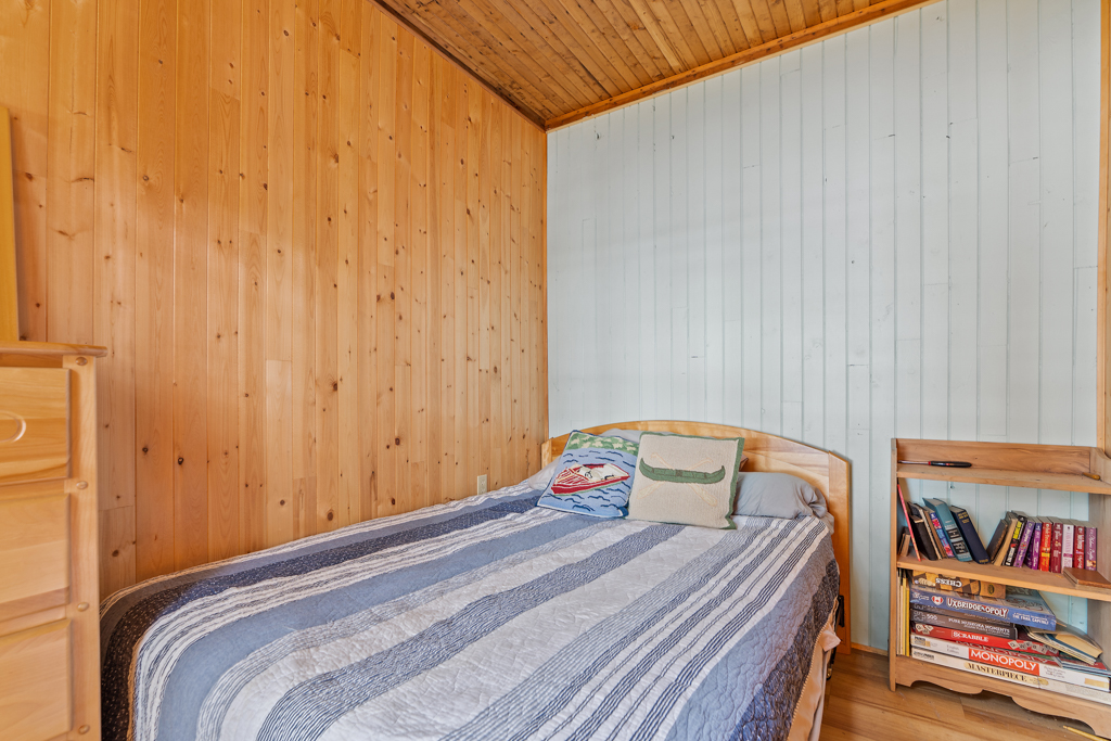 A small bedroom with wood-panelled walls and a bed.