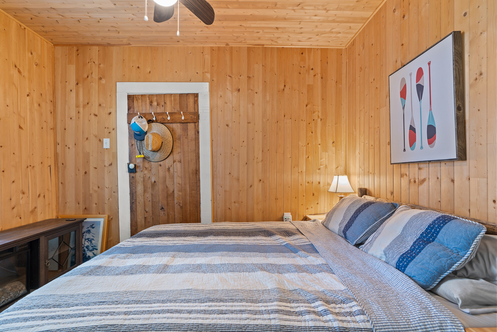 A small bedroom with wood-panelled walls and a big bed.