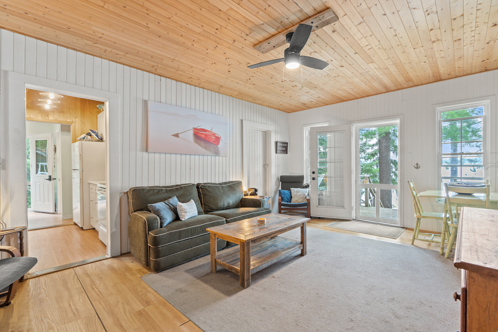 A bright, open cottage living space with a small dining table, a couch, and a coffee table.