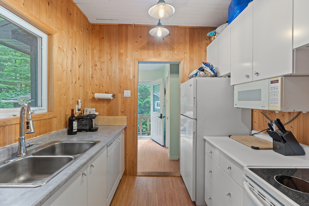 A narrow kitchen with wood-panelled walls.