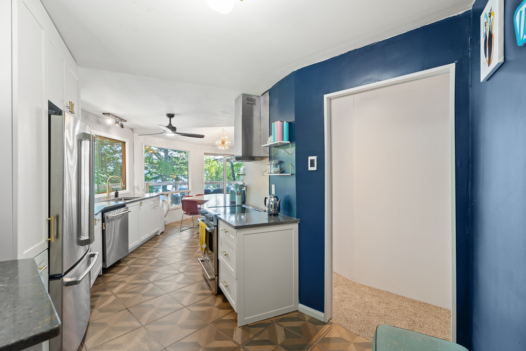 Inside the entrance of a cottage, a narrow kitchen curves off to the left. There is an open doorway straight ahead.